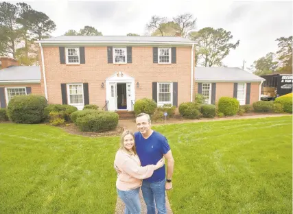  ?? BILL TIERNAN/FREELANCE ?? Jennifer and Tom Karness stand in front of their new home in Virginia Beach on March 24 — their moving day. The couple’s bid for the home was $50,000 above the listed price.