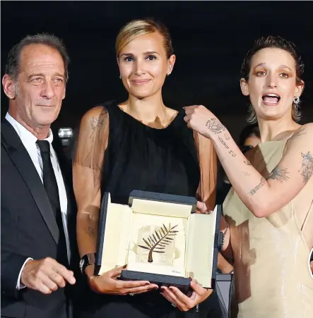  ?? PHOTO AFP ?? La réalisatri­ce française Julia Ducournau et les deux principaux acteurs de Titane, Vincent Lindon et Agathe Rousselle, prennent la pose avec la Palme d’or lors de la séance photo qui a suivi la remise de prix.