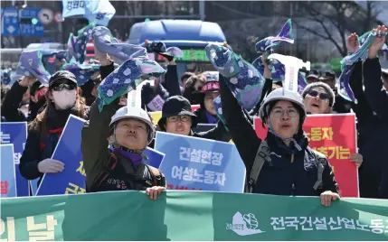  ?? Photo by Jung Yeon-je / AFP ?? South Korean workers wave scarves as they march during a rally to mark Internatio­nal Women’s Day in downtown Seoul on March 8, 2024.