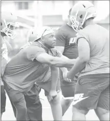  ??  ?? At left, Forrest City Junior Mustangs assistant coach Kevin Mosley shows a Junior Mustangs lineman the proper technique to use during a running play on Monday.