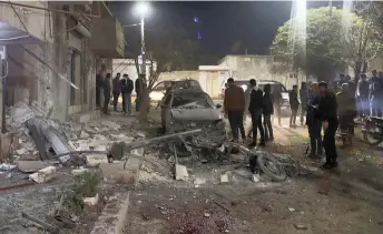  ?? — AFP photo ?? Syrian civilians stand at the scene of a rocket attack in the town of Azaz in the rebel-held north of the Aleppo province.