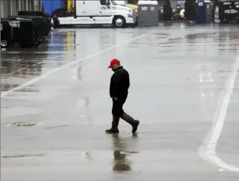  ?? Associated Press ?? A man walks through the trailer area at a wet and rainy Charlotte Motor Speedway Wednesday night in Concord, N.C. The weather forced postponeme­nt of the scheduled NASCAR Cup series race.