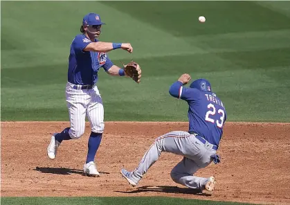  ?? AP Photo/Ashley Landis ?? ■ Chicago Cubs shortstop Nico Hoerner, left, throws to first for a double play during the second inning of a spring training baseball game Monday in Mesa, Ariz. Texas Rangers Jose Trevino (23) was out at second, and Nate Lowe was out at first.