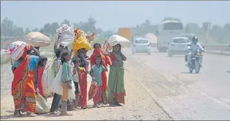  ?? DEEPAK GUPTA/HT ?? Migrants looking to hitch a ride on passing vehicles or arrange other means of transporta­tion to their homes.