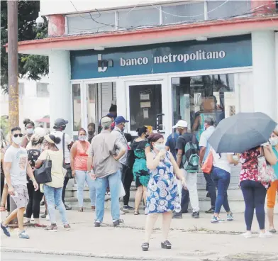  ?? efe / yander zamora ?? Varias personas esperan su turno para entrar a un banco, en La Habana (Cuba). Tras la decisión del gobierno cubano de suspender los depósitos bancarios en dólares en efectivo se espera que la “divisa verde” sea destronada por el euro y este dispare su valor en el mercado informal.