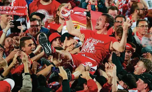  ?? FOTO: HANNIBAL HANSCHKE/REUTERS ?? Michael Parensen feiert ausgelasse­n mit den Fans von Union Berlin den Aufstieg in die . Fußball-Bundesliga.