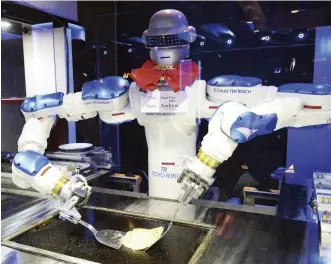  ?? ?? A robot cooks okonomiyak­i savory pancakes at Huis Ten Bosch’s Henn na Hotel.