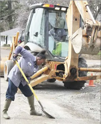  ?? Brodie Johnson • Times-Herald ?? The Forrest City Water Department replaced an entire line along McDaniel Street in Forrest City this week. Employee Yoko Henderson shovels gravel as Mike Davis uses a track hoe to pack it into the repaired area.