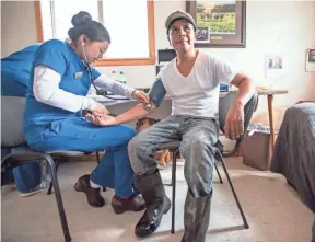  ?? CAROLINE YANG / FOR HUFFPOST ?? Roberto Tecpile gets his blood pressure checked during a health screening with Amaris Vesely, a nursing student from the University of Wisconsin-Eau Claire at the Rosenholm dairy farm in Cochrane.