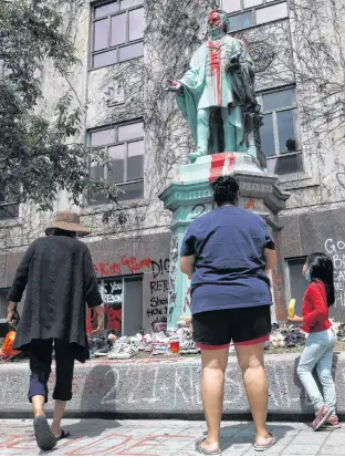  ?? REUTERS ?? A First Nations family views the defaced Ryerson University statue of Egerton Ryerson, considered an architect of Canada’s residentia­l Indigenous school system, in Toronto on Wednesday.