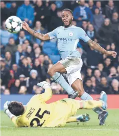  ??  ?? Raheem Sterling (top) lifts the ball over Feyenoord’s Australian goalkeeper Brad jones to score the opening goal during the UEFA Champions League Group F football match between Manchester City and Feyenoord at the Etihad Stadium in Manchester, north...