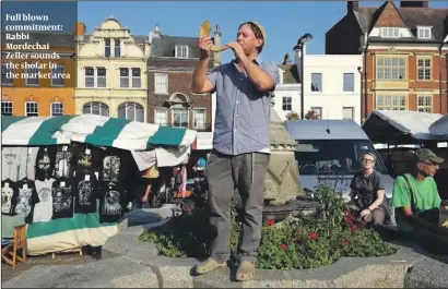  ??  ?? Full blown commitment: Rabbi Mordechai Zeller sounds the shofar in the market area