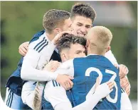  ??  ?? Oliver Burke is mobbed after his goal in Latvia