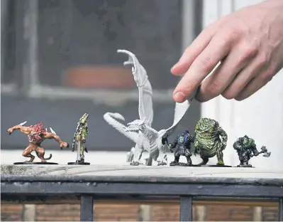  ??  ?? Dungeon Master Harlan Kelly sets up Dungeons and Dragons figurines on his balcony in Denver on May 13.