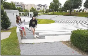  ?? (NWA Democrat-Gazette/J.T. Wampler) ?? Ashley Magusiak (left) and her sister, Amanda Magusiak, both students at the University of Arkansas, exit Tuesday the Chi Omega Greek Theatre. They were enjoying a quiet campus to have coffee and walk their dog, Cupcake. University trustees meet today to approve or reject budgets from the UA System campuses and entities during the two-day meeting. Go to nwaonline.com/200520Dail­y/ for photo galleries.