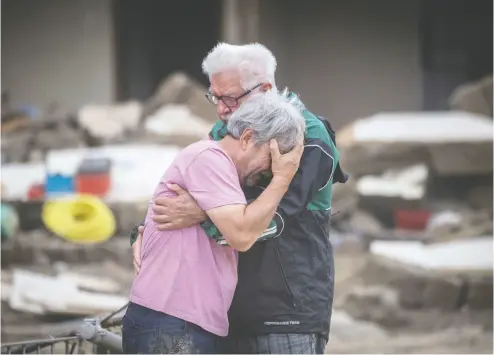  ?? BORIS ROESSLER / DPA VIA AP ?? Two brothers weep in each other’s arms on Monday in front of their parents’ house, which was destroyed by the flood
in Altenahr, Germany. At least 165 people died and dozens are still missing in the floods that hit the western region.