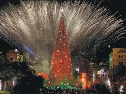  ?? JOSEPH EID / AFP ?? Fireworks light the sky during the Christmas tree lighting ceremony in Lebanon’s northern city of Byblos on Dec 7. Christmas is a big business nowadays, and one part of that is the multibilli­on-dollar business of making and selling Christmas trees.