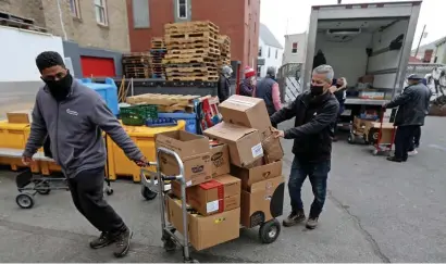  ?? STuART cAHiLL pHOTOS / HERALD STAFF ?? DELIVERY: Lovin’ Spoonfuls makes a milestone delivery of its 20 millionth pound to food to pantries, this one to Everett Grace Food Pantry, on Thursday. At right, Vincent Vassallo moves a box.