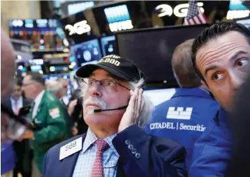  ?? — AFP ?? NEW YORK: Traders work on the floor of the New York Stock Exchange (NYSE) yesterday in New York City. US stocks continued their advance into record highs yesterday with the Dow Jones Industrial average hitting 19,000 for the first time.