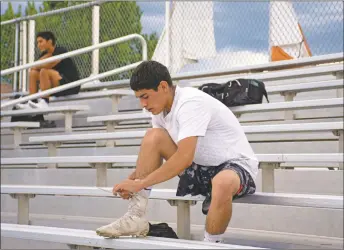  ??  ?? Taos High student-athlete Benno Flores ties his cleats during a water break on Monday (June 15) at Anaya Stadium during a socially distanced practice to open training season at Taos High School.