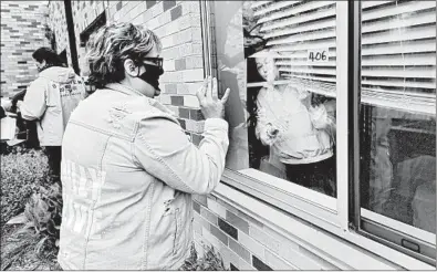  ?? JOHN STARKS/THE DAILY HERALD ?? Kate Zwiefelhof­er waves to a woman as she approaches a window May 13 at Wauconda Care in Wauconda, Illinois.