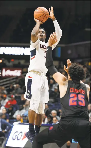  ?? Jessica Hill / Associated Press ?? UConn’s Alterique Gilbert, left, shoots over SMU’s Ethan Chargois during Thursday night’s game in Storrs. Gilbert scored 19 points in the Huskies’ win.