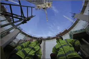  ?? (AP/Kin Cheung) ?? Employees look up at the constructi­on site of Hinkley Point C nuclear power station in Somerset, England, in October 2022.