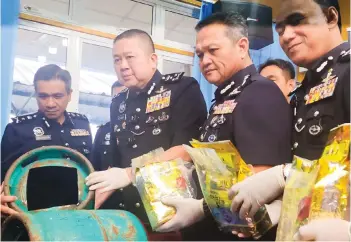  ?? — Photo by Roystein Emmor ?? Khaw (second left) shows a gas tank used to distribute the drugs. On his left is Sarawak Police Commission­er Datuk Mancha Ata.