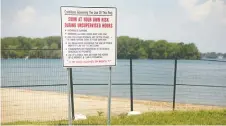  ??  ?? A sign warning to swim at your own risk during unsupervis­ed hours is posted at Sand Point Beach. People recently pushed open the fence to swim.