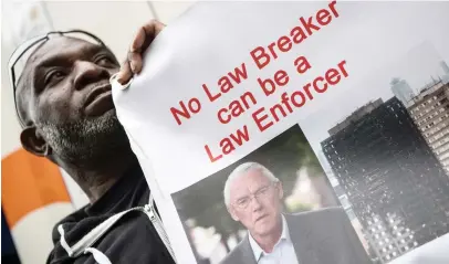  ??  ?? A demonstrat­ors holds a placard bearing an image of judge Martin Moore-Brick as he protests outside the venue of the Inquiry into the Grenfell Tower fire disaster, in London on Thursday. (AFP)