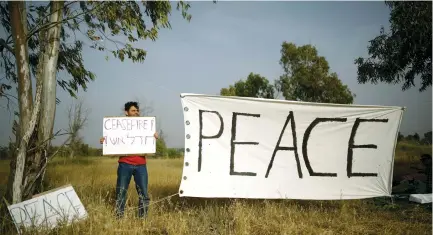  ?? (Reuters) ?? A PEACE activist holds up a sign near Gaza.