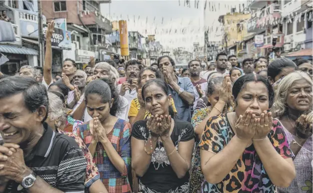  ?? PICTURE: CARL COURT/GETTY IMAGES ?? 0 Sri Lankans pray in the street near St Anthony’s Shrine one week on from the attacks that killed more than 250 people in Colombo