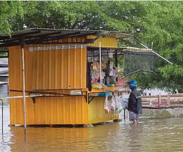  ?? NSTP PIC BY GHAZALI KORI ?? A man buying goods from a stall that is still open despite the floods in Kampung Baru Kemasik, Kemaman, yesterday.