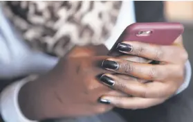  ??  ?? Yvette Mbabazi, who uses social media to promote herself and her business marketing brands, labels and fashions, checks her iPhone in Kigali.