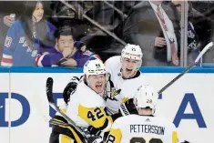  ?? ADAM HUNGER THE ASSOCIATED PRESS ?? Pittsburgh’s Evgeni Malkin, centre, celebrates after scoring in the third overtime in Game 1 of their opening playoff series in New York on Tuesday night. The Penguins won 4-3.