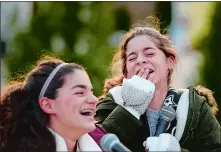  ?? SARAH GORDON/THE DAY ?? The Rossi Sisters, Rosie, left, 13, and Annie, 10, laugh as they perform Christmas songs during the Niantic Main Street Holiday Stroll in November. The sisters perform locally, playing the piano, guitar and ukulele and also have sung “God Bless...