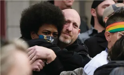  ?? Photo: AP. ?? Nic Grzecka, right, co-owner of Club Q, hugs a supporter after a 25-foot historic pride flag was unfurled to cover the exterior of City Hall to mark the weekend mass shooting at the gay nightclub, Wednesday.