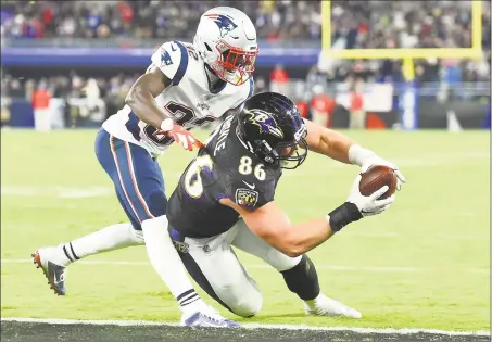  ?? Will Newton / Getty Images ?? Ravens tight end Nick Boyle scores a touchdown in front of Patriots safety Devin McCourty during the fourth quarter on Sunday at M&T Bank Stadium in Baltimore.