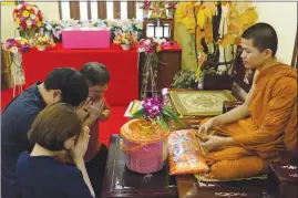  ?? AMANDA MUSTARD / THE NEW YORK TIMES ?? The family of Nomsod, a 10-month-old Pomeranian who died of kidney failure, makes an offering to a monk during a funeral at a Buddhist temple in Bangkok.