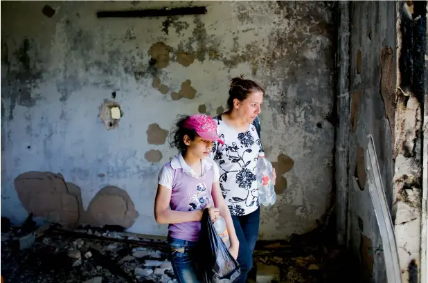  ?? —AP ?? Adibeh Ghosn and her daughter, Samar, pick through the heaps of trash littering their home in Zabadani which they left five years ago. The town now has only pulverised buildings unfit for residence.