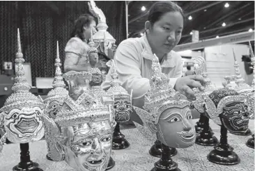  ??  ?? A woman sets up rows of traditiona­l masks at the SME Expo. Small businesses, which account for 95% of all businesses in Thailand, stand to be severely affected by losses at the SME Bank.