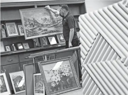  ?? PHOTOS BY RYAN GARZA/DETROIT FREE PRESS ?? Aaron’s Estate Sales owner Aaron Siepierski looks over artwork owned or made as part of the Sisters of Mercy convent estate sale on Tuesday.