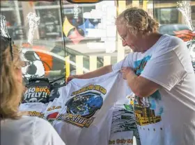  ?? Alex Caprara/Post-Gazette ?? At B.A. Trading on 18th Street and Penn Avenue in the Strip District on Friday, Rich Radwanski displays a T-shirt highlighti­ng the upcoming Penguins-Sharks matchup in the Stanley Cup Finals that begin Monday at the Consol Energy Center.