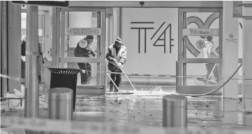  ??  ?? Workers sweep water from floor of the arrivals area at John F Kennedy Internatio­nal airport’s terminal 4, in New York. — AFP photo
