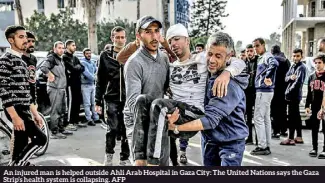  ?? ?? An injured man is helped outside Ahli Arab Hospital in Gaza City: The United Nations says the Gaza Strip’s health system is collapsing. AFP