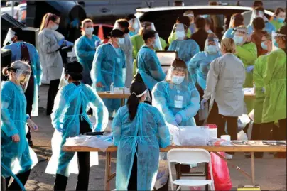  ?? The Associated Press ?? FRONT LINE: Medical personnel prepare to test hundreds of people lined up in vehicles on June 27 in Phoenix’s western neighborho­od of Maryvale for free COVID-19 tests organized by Equality Health Foundation, which focuses on care in underserve­d communitie­s. The personal protective gear that was in dangerousl­y short supply during the initial weeks of the coronaviru­s crisis in the U.S. is running out again as the virus resumes its rapid spread and the number of hospitaliz­ed patients climbs.