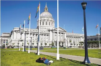  ?? Photos by Paul Chinn / The Chronicle ?? Left: A man sleeps in Civic Center Plaza in front of City Hall, in a neighborho­od that teems with San Francisco’s homeless population.
Below left: A woman reclines with her dogs at the top of the BART escalator at the city’s Embarcader­o station.