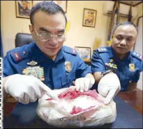  ?? BOY SANTOS ?? Chief Superinten­dent Guillermo Eleazar and Superinten­dent Robert Sales inspect two kilos of high-grade shabu, found in the ceiling of an apartment in Quezon City, during a press conference yesterday.