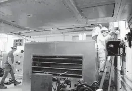  ??  ?? Constuctio­n workers work on the AC system at James S. Rickards Middle School in Oakland Park on Friday.