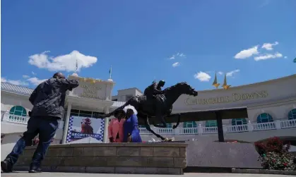  ?? Photograph: Kiichiro Sato/AP ?? Race fans take photos in front of a statue of Barbaro at Churchill Downs on Thursday. Barbaro won the 2006 Kentucky Derby but shattered his leg two weeks later in the Preakness Stakes which led to him being euthanized.